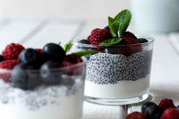 Chía with wild berries. Raspberries and blueberries. Delicious and healthy dessert with white background over a white wood rustic table.