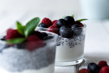 Chía with wild berries. Raspberries and blueberries. Delicious and healthy dessert with white background over a white wood rustic table.
