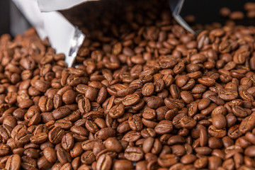 Packing with grains of coffee on a black background. Close-up. Space for text.
