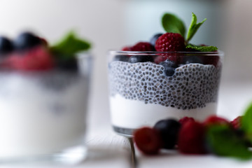 Chía with wild berries. Raspberries and blueberries. Delicious and healthy dessert with white background over a white wood rustic table.