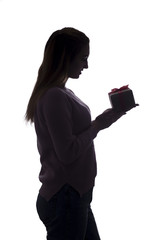 silhouette of a young woman with a gift in hands, girl with a box with a bow on a white isolated background,concept of holidays