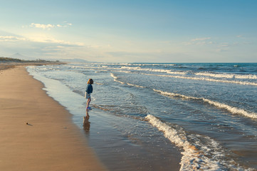 Little girl stepping into sea during her family day out on the beach.