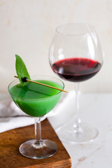 Aperitif with Chianti red wine, and green cocktail with kiwi and prosecco, garnished with sage leaf