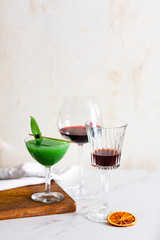 Aperitif with Chianti red wine, red Vermouth and green cocktail with kiwi and prosecco, garnished with sage leaf