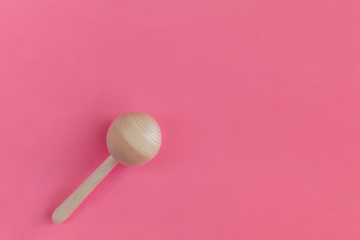 Wooden baby rattle on a pink background. Flat lay, hand made, copy space, top view, toy.