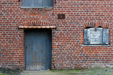 Rote Backsteinwand  mit einer Blauen alten verwitterten Tür als Hintergrund oder Textur