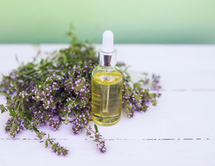 cosmetic bottle with a pipette and lavender oil lies on a wooden table next to delicate lilac...