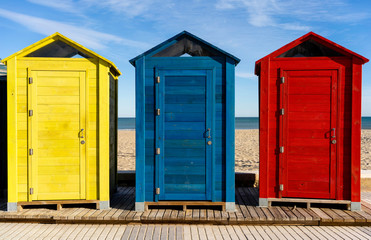 row of beach huts cabins in front of beach see and sand