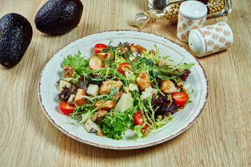 Juicy, green salad with roquefort cheese, blue cheese lettuce, sesame seeds, avocado and teriyaki chicken and cherry tomatoes in a blue bowl on a wooden background. Healthy food. Fitness nutrition