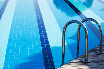 Obraz premium Outdoor large blue swimming pool on site with stairs to descend into the water. There is room for text.