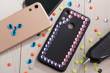 Attaching colorful rhinestones onto phone cases with a glue gun