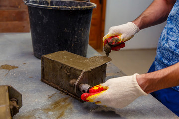 A member of the construction of the laboratory takes a sample of concrete. He loads the concrete...