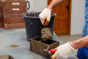 A member of the construction of the laboratory takes a sample of concrete. He loads the concrete...