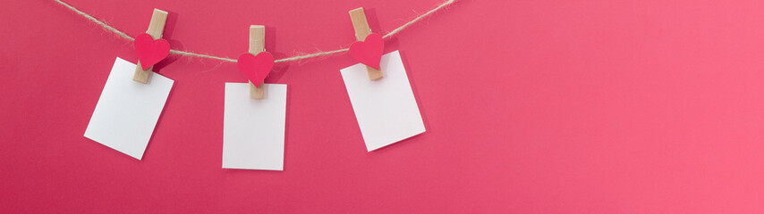 I love you - Clothes pegs with wooden hearts and paper notes hang on rope isolated on pink texture background panorama banner long, with space for text