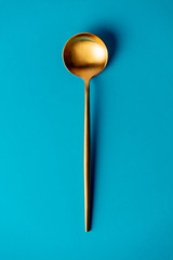 golden spoon on blue background isolated