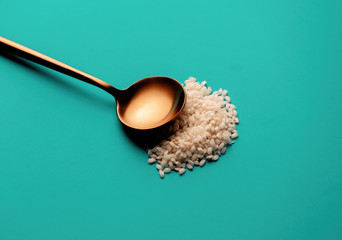 golden spoon with rice grains on Aqua Menthe color background