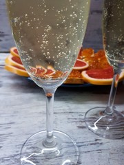  close-up of champagne glasses with blur / bokeh effect, on the background of sliced ​​grapefruit and sandwiches with red caviar on a blue plate