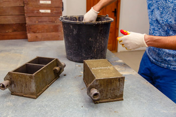 A member of the construction of the laboratory takes a sample of concrete. He loads the concrete...