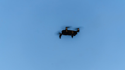 Single drone in the air, flying in front of dark green jungle. Lens and camera are directed towards the photographer.