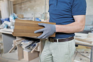 Wooden details in hands of male carpenter, woodworking industry