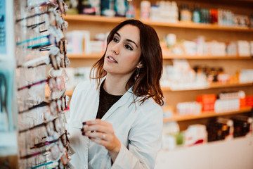 .Young female pharmacist working in her large pharmacy. Placing medications, taking inventory. Lifestyle