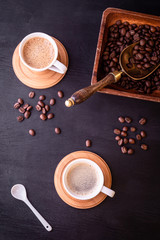 Coffee theme. Flat lay. Hot cups of coffee and plate with coffee beans on black wooden table.