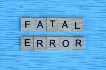 phrase fatal error made from gray wooden letters lies on a blue background
