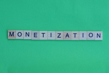 word monetization made of small gray wooden letters on a green paper background