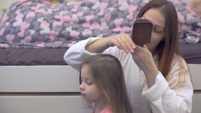 mom gently brush your little daughter's hair
