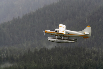 Juneau, Alaska, United States. Floatplane flying near a small touristic town during a rainy morning.