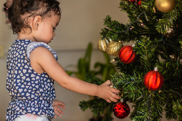 Child girl looking at christmas spheres on a christmas tree