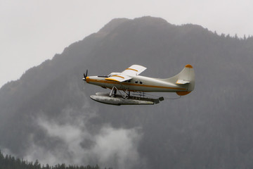 Juneau, Alaska, United States. Floatplane flying near a small touristic town during a rainy morning.