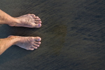 Human barefoot feet in wet sand on sea shore, active healthy living and personal growth concept,...