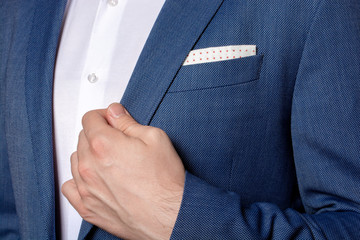 Male hand of businessman holding the edge of his classic blue blazer  - obrazy, fototapety, plakaty