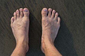 Fototapeta premium Human barefoot feet in wet sand on sea shore, active healthy living and personal growth concept, copy space