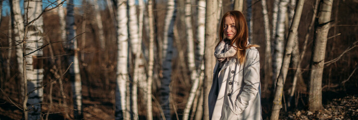 Portrait of a girl on the background of trees in early spring at sunset.