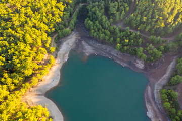 Natural lake surrounded by pine trees, mountains and a village.