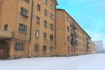 Strong snowstorm in the city against the background of old houses and blue sky
