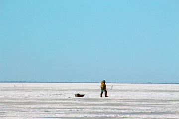 a man walking on a frozen sea with a sled and a rotor