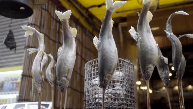 Japanese grilled ayu fish or sweetfish skewered on sticks, rotating left medium shot