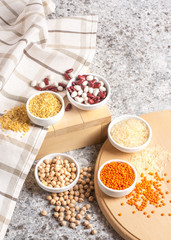 Set of raw legumes, beans, chickpeas, lentils and cereals, rice and bulgur on a wooden tray on a gray background. Healthy food, Protein source for vegetarian.