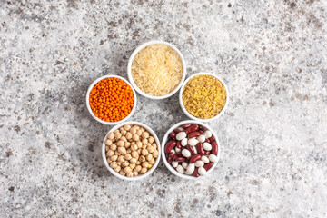 Set of raw legumes, beans, chickpeas, lentils and cereals, rice and bulgur on a gray background. Healthy food, Protein source for vegetarian.