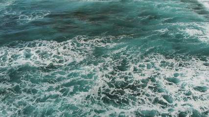 Top view of the Atlantic Ocean, small waves create sea foam near the beach