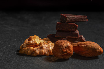 Dark chocolate in nuts on a stone. Dark background
