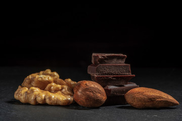 Dark chocolate in nuts on a stone. Dark background