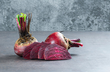 Fresh organic whole and sliced red beet, beetroot on rustic table, healthy food beta vulgaris