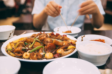A Close up of Korean chicken dish on a table at a restaurant with a mid section of a person in the background 