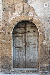 Old wooden door in the stone wall. 