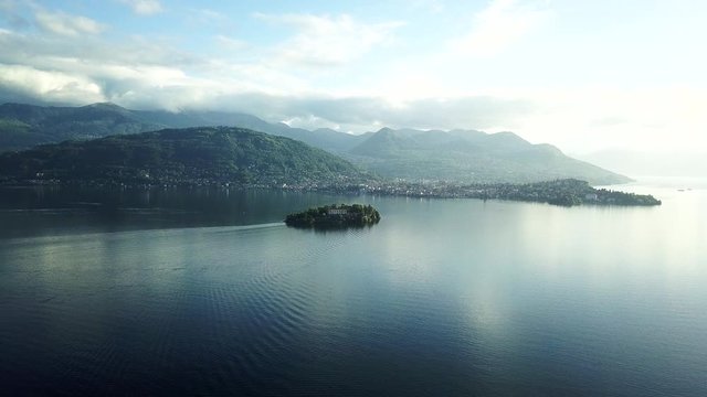 Early morning drone shooting. Lake Maggiore in the distance shows the island of Scoglio della Malghera. Northern Italy surrounded by mountains.
