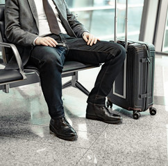 man waiting for his flight at the airport and looking at a mobile phone